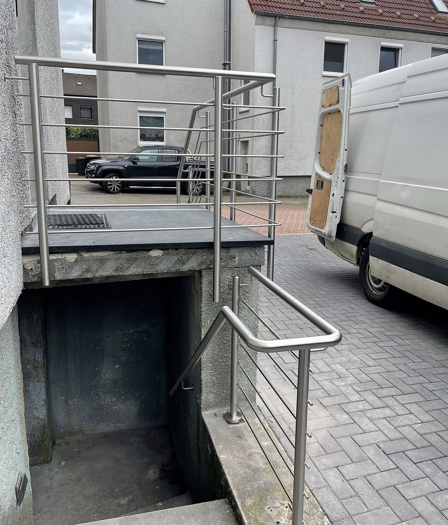 Edelstahlgeländer an einem Eingangspodest mit Handlauf zur Kellertreppe