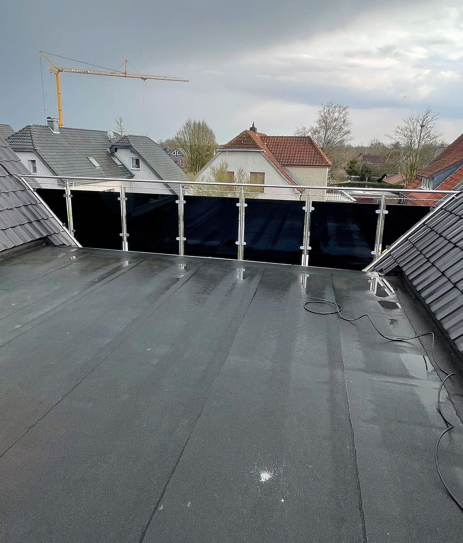 Geländer mit dunklen Glasfeldern und Edelstahlhandlauf auf einer Dachterrasse