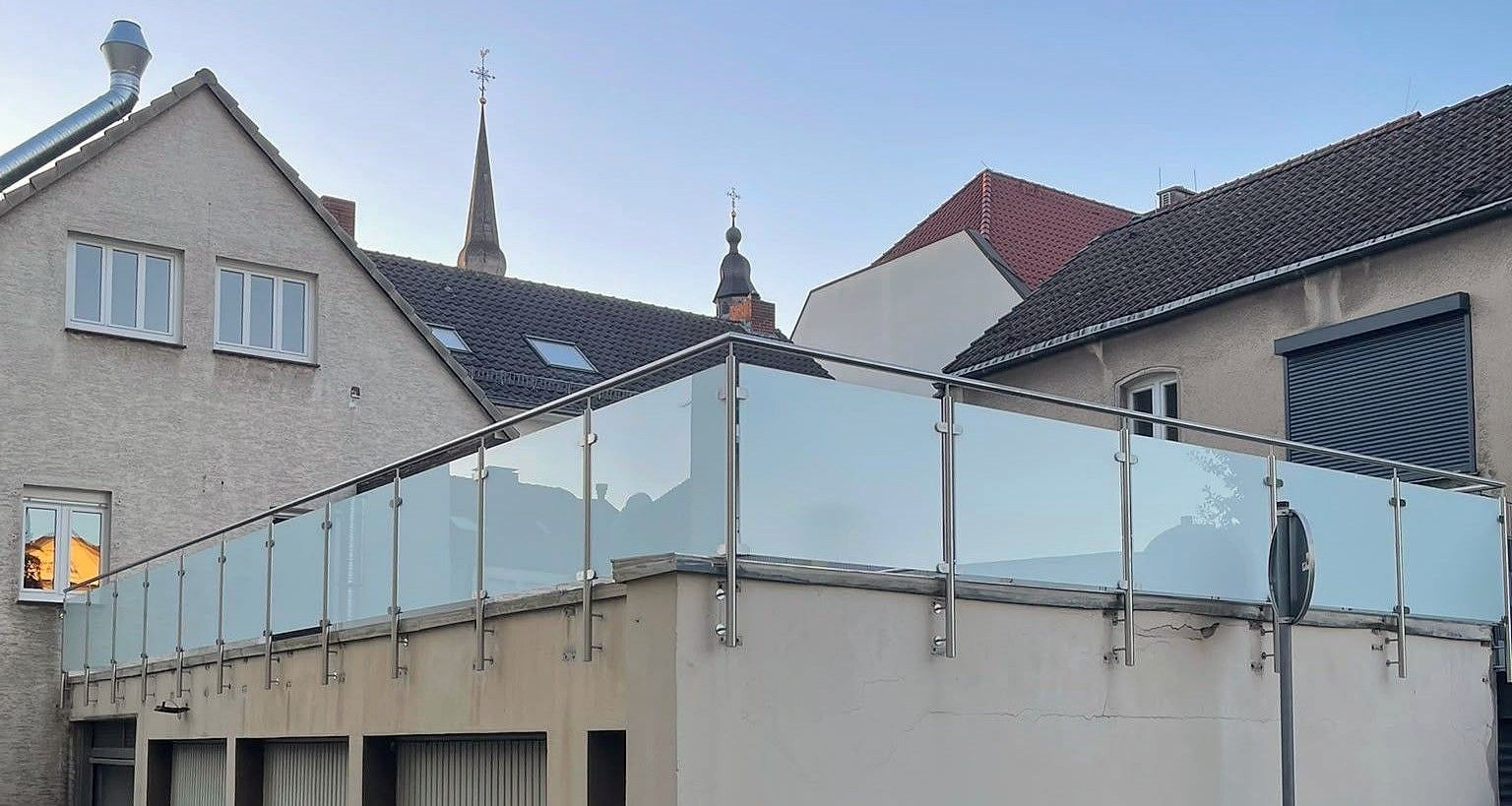 Geländer mit Milchglas und Edelstahlpfosten auf dem Dach einer Garagenzeile
