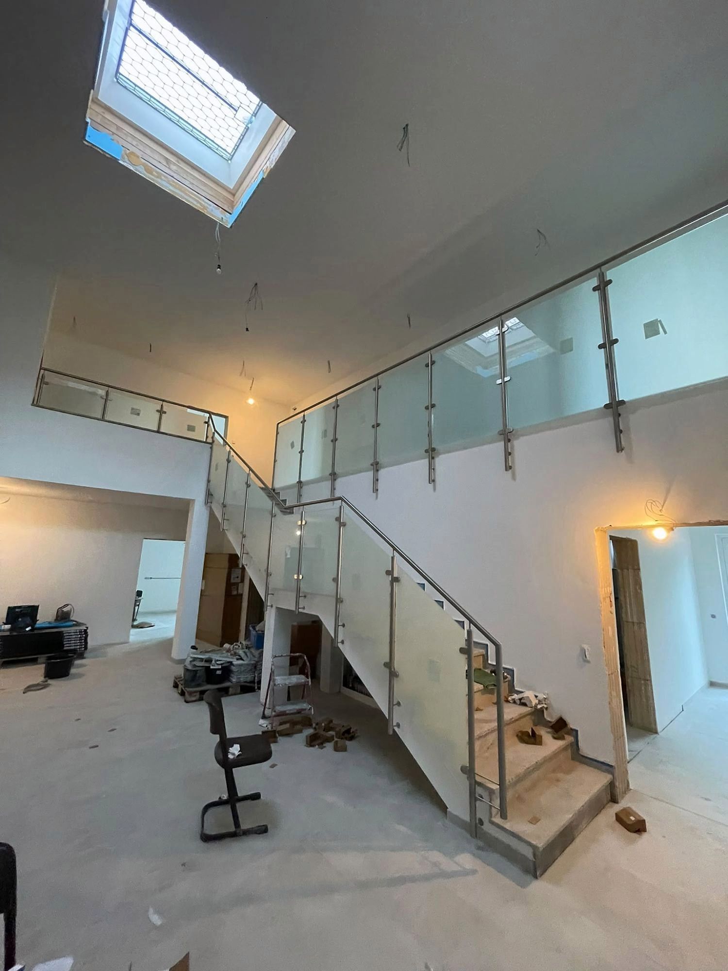 Glasgeländer mit Edelstahlpfosten an Treppe und Galerie in einer hohen Halle